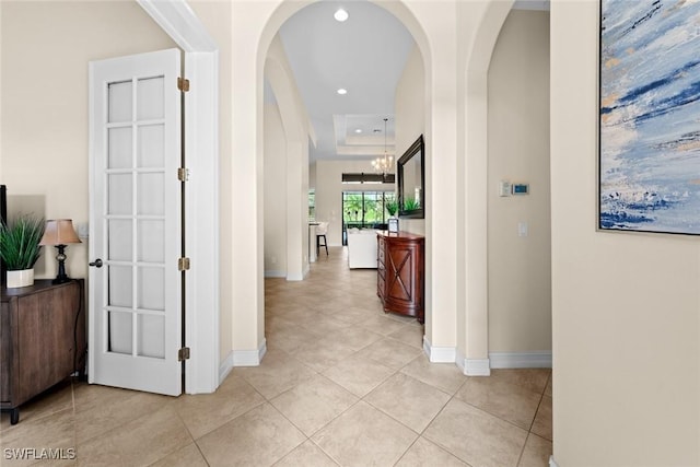 hallway featuring light tile patterned floors and a raised ceiling