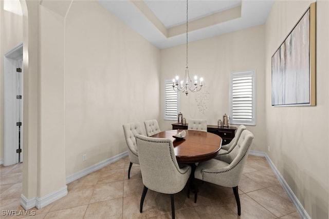 dining space featuring a notable chandelier, a tray ceiling, and light tile patterned floors