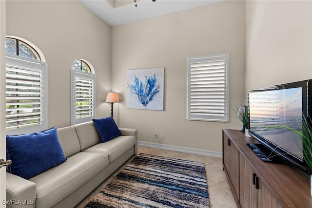 tiled living room with ceiling fan and a high ceiling