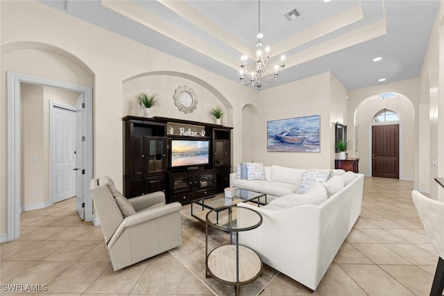 tiled living room with a chandelier and a tray ceiling