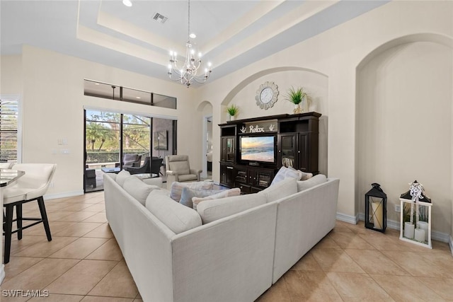 living room with light tile patterned flooring, a notable chandelier, and a tray ceiling