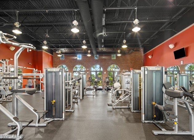 workout area with rail lighting, brick wall, and a towering ceiling