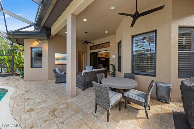 view of patio featuring outdoor lounge area, ceiling fan, and glass enclosure