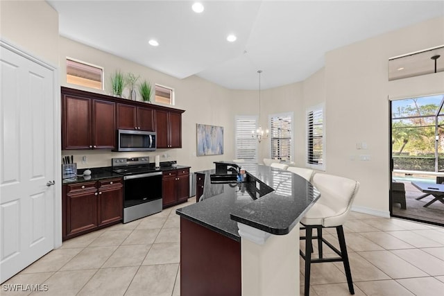 kitchen featuring sink, dark stone counters, a kitchen breakfast bar, a notable chandelier, and stainless steel appliances