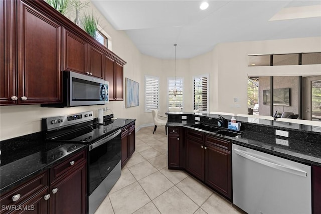 kitchen with appliances with stainless steel finishes, sink, hanging light fixtures, and dark stone counters