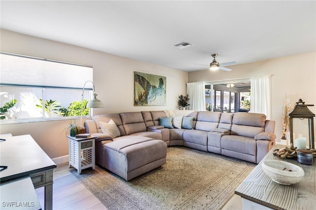 living area with light wood-style flooring, baseboards, visible vents, and ceiling fan