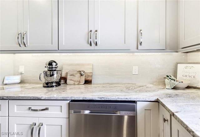 kitchen featuring tasteful backsplash, white cabinets, dishwasher, and light stone countertops