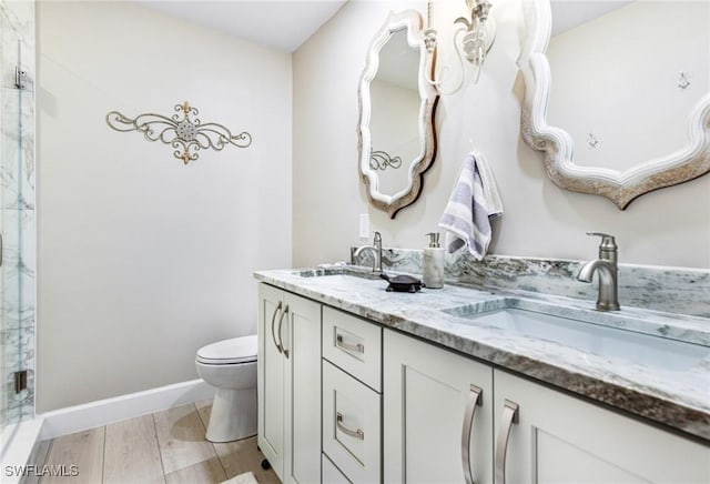 full bath with a sink, toilet, double vanity, and a shower stall