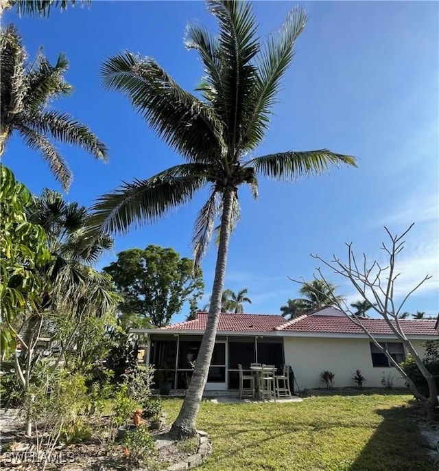 back of house with a lawn and a sunroom