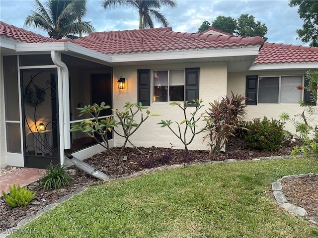 view of front facade with stucco siding, a tiled roof, and a front lawn