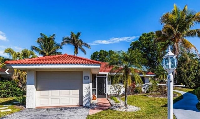 view of front of home featuring a front yard, aphalt driveway, an attached garage, stucco siding, and a tile roof