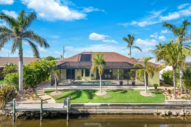 back of property featuring a water view, glass enclosure, a patio area, and a yard