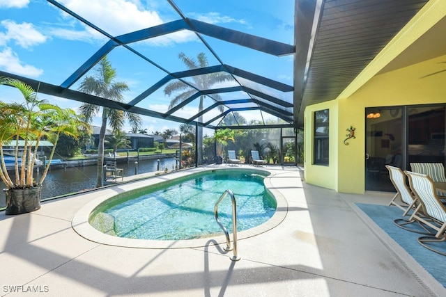 view of swimming pool with glass enclosure, a water view, and a patio area