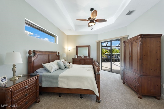 carpeted bedroom featuring ceiling fan, a raised ceiling, and access to exterior