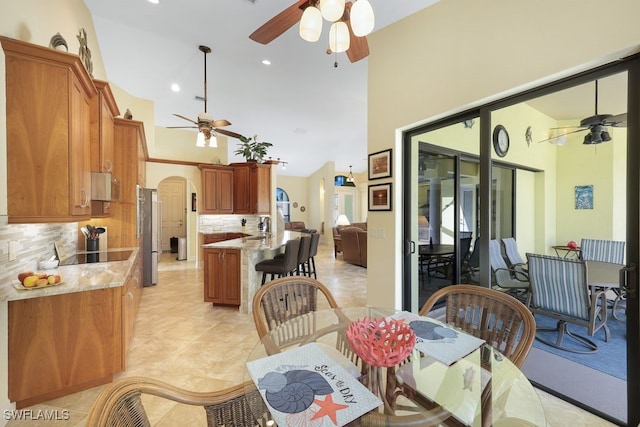 dining space featuring a high ceiling, sink, light tile patterned flooring, and ceiling fan