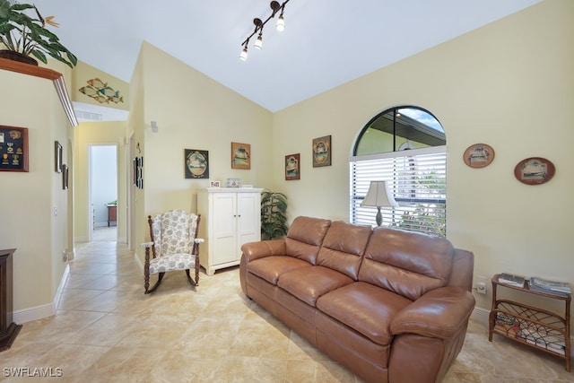 tiled living room featuring lofted ceiling and track lighting