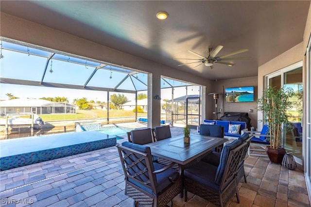 view of patio / terrace featuring a swimming pool with hot tub, ceiling fan, and glass enclosure