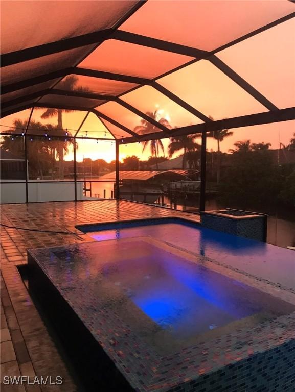 pool at dusk with a lanai and a patio area