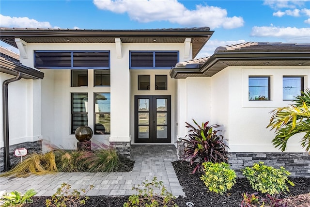 doorway to property with french doors, a tile roof, and stucco siding