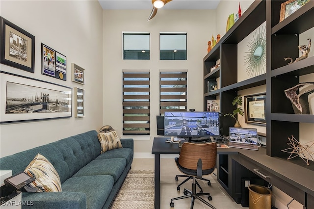 office area featuring ceiling fan, light tile patterned flooring, and a towering ceiling