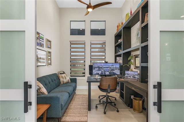 office area featuring a ceiling fan, a towering ceiling, and tile patterned floors