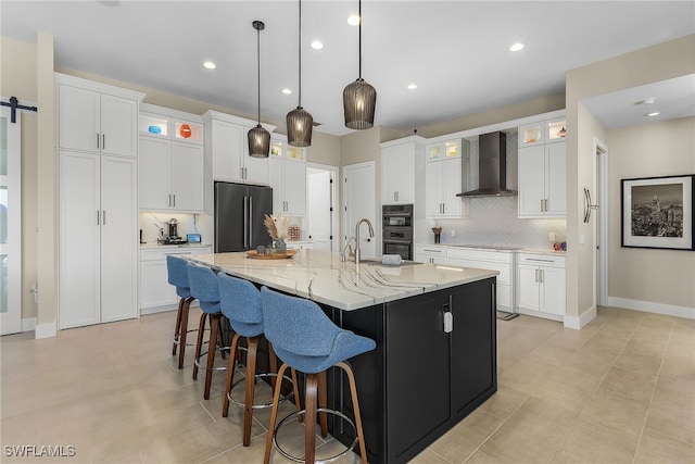 kitchen featuring a barn door, white cabinets, a spacious island, wall chimney range hood, and black appliances