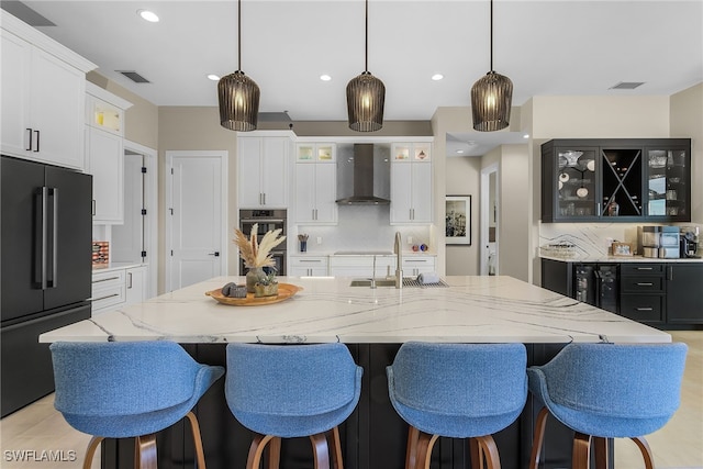 kitchen featuring double oven, a sink, visible vents, freestanding refrigerator, and wall chimney exhaust hood