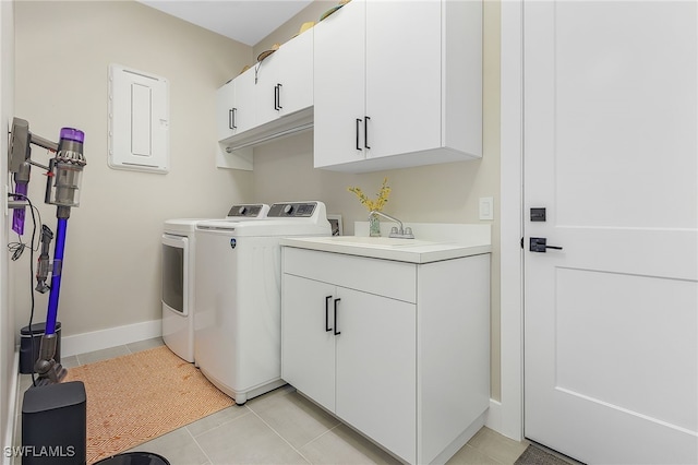 washroom with light tile patterned flooring, a sink, baseboards, cabinet space, and washing machine and clothes dryer