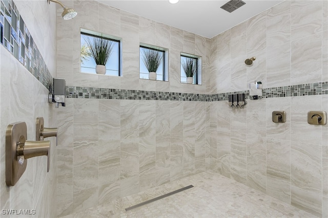 full bathroom with a tile shower and a wealth of natural light