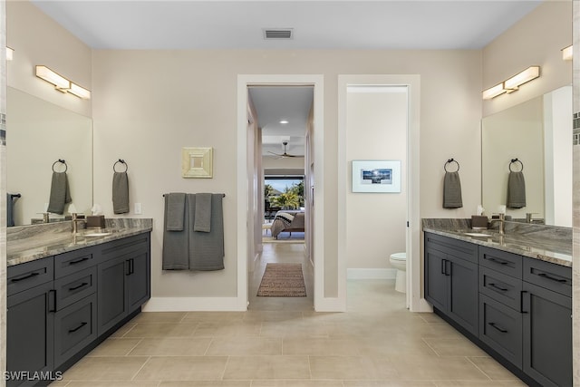 bathroom with two vanities, visible vents, toilet, a sink, and baseboards