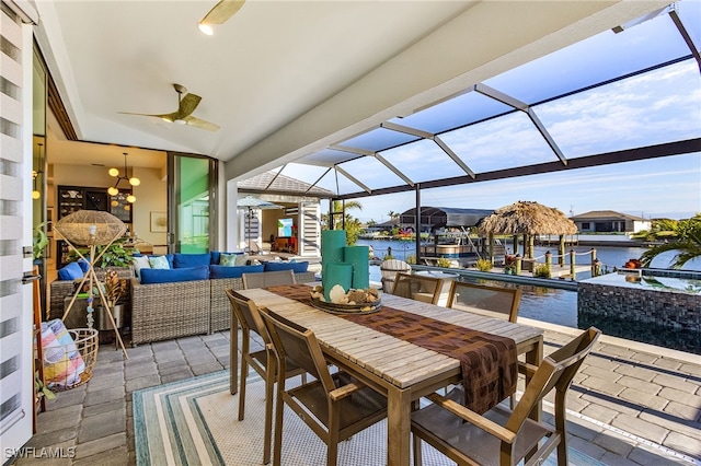 exterior space featuring outdoor dining area, a water view, ceiling fan, a dock, and a lanai