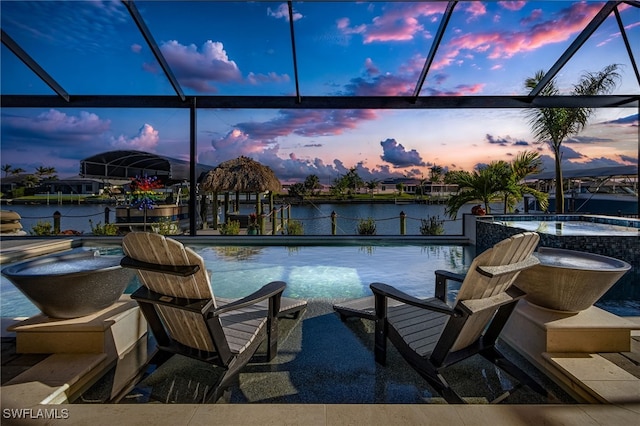 view of pool with a dock, glass enclosure, a water view, and a pool with connected hot tub