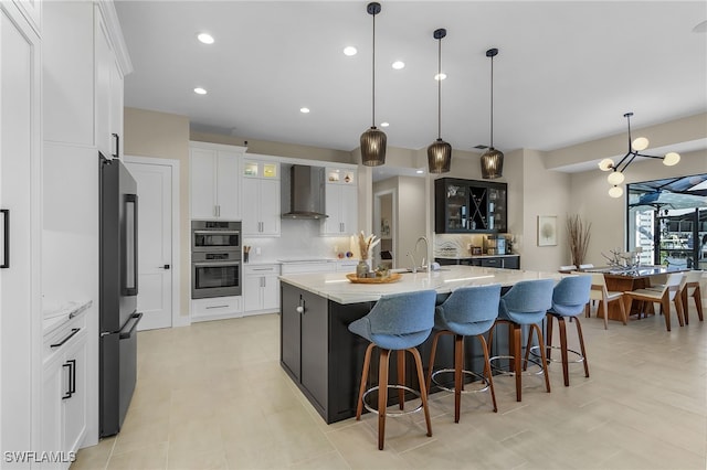 kitchen with tasteful backsplash, a spacious island, appliances with stainless steel finishes, wall chimney range hood, and a sink