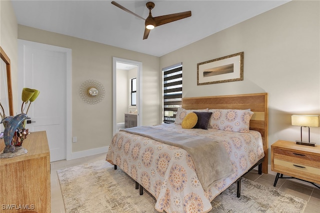 bedroom featuring ensuite bathroom, tile patterned flooring, a ceiling fan, and baseboards