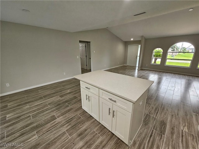 kitchen with white cabinetry, vaulted ceiling, and a center island