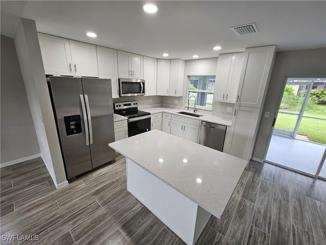 kitchen with light stone counters, stainless steel appliances, sink, and white cabinets