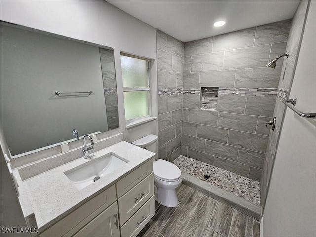 bathroom featuring vanity, tiled shower, and toilet