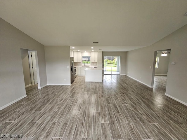 unfurnished living room featuring hardwood / wood-style flooring, sink, and vaulted ceiling