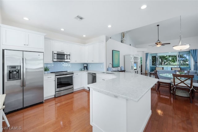 kitchen with pendant lighting, sink, white cabinetry, stainless steel appliances, and kitchen peninsula