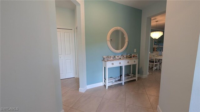 hallway featuring an inviting chandelier and light tile patterned floors