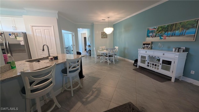 kitchen with hanging light fixtures, a kitchen breakfast bar, stainless steel refrigerator with ice dispenser, light stone counters, and white cabinets