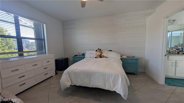 tiled bedroom featuring ceiling fan and ensuite bath