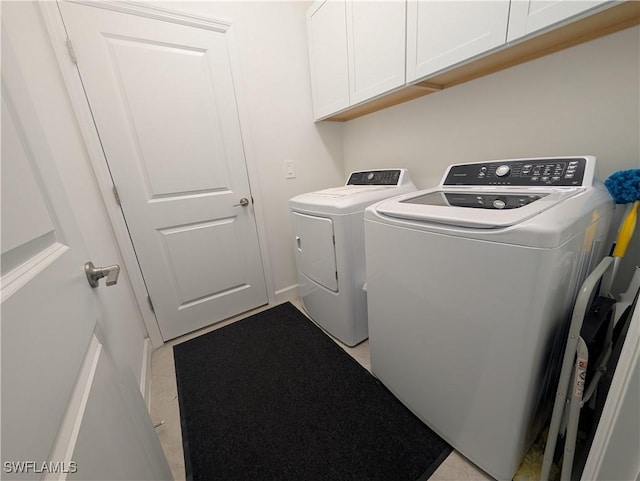 clothes washing area featuring cabinets and washing machine and dryer