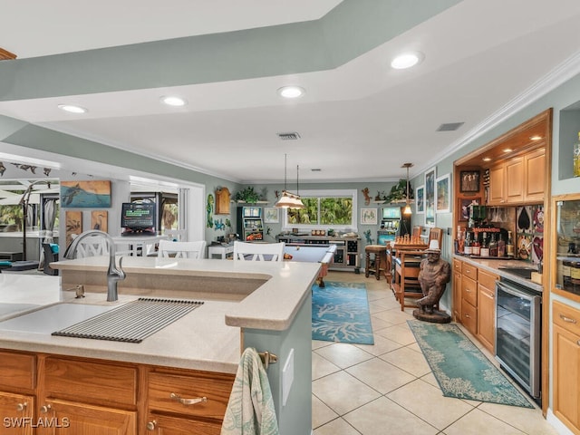 kitchen with hanging light fixtures, light tile patterned floors, ornamental molding, and beverage cooler