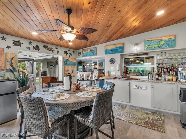 dining space featuring wood ceiling, ceiling fan, bar area, and light hardwood / wood-style floors