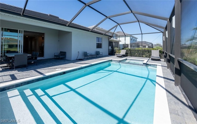 view of pool with a jacuzzi, a patio area, and glass enclosure