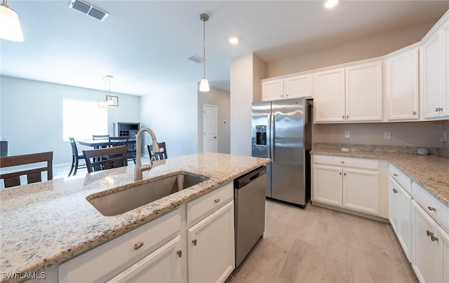 kitchen with sink, white cabinetry, hanging light fixtures, stainless steel appliances, and light stone countertops