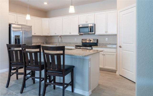 kitchen with white cabinetry, pendant lighting, stainless steel appliances, and a kitchen breakfast bar