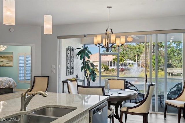 kitchen with sink, dishwasher, light stone counters, a notable chandelier, and decorative light fixtures