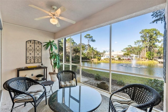 sunroom with ceiling fan and a water view